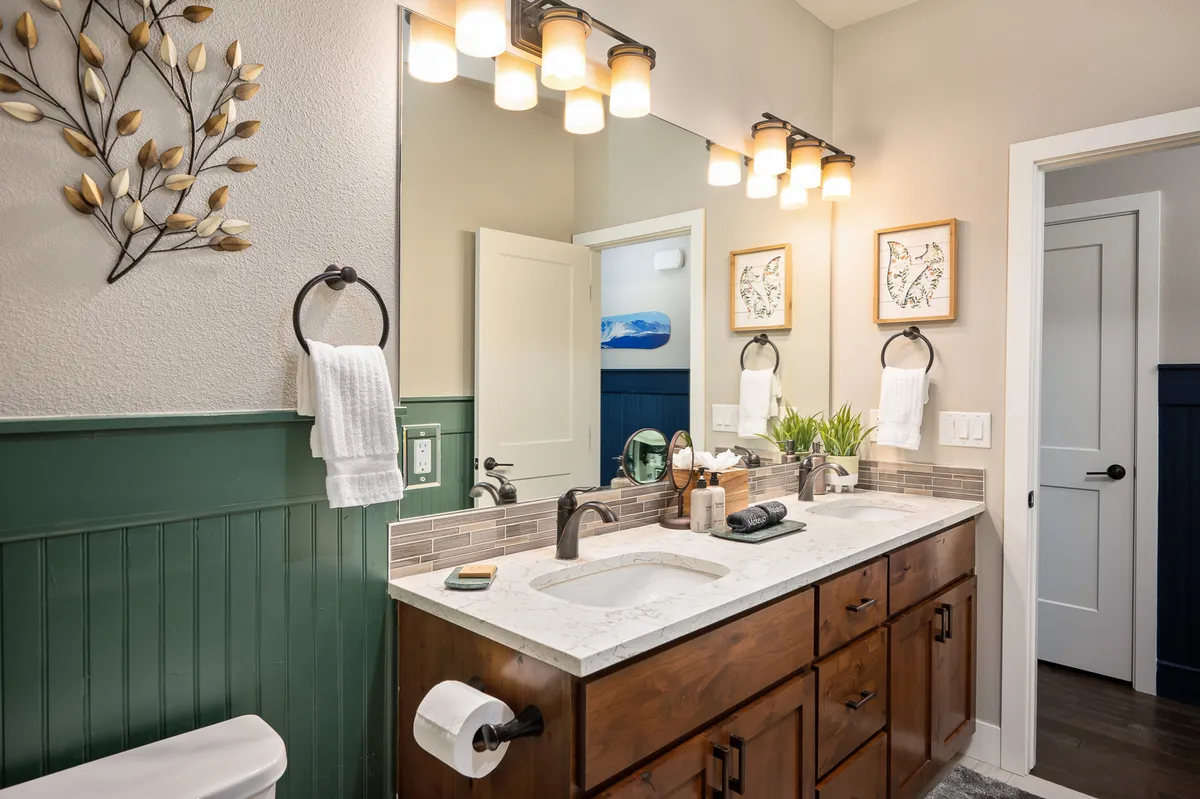 A modern bathroom with a double sink vanity, framed artwork, and thoughtful decorative accents. The space is designed for both function and relaxation, offering an organized and soothing environment for morning and evening routines.