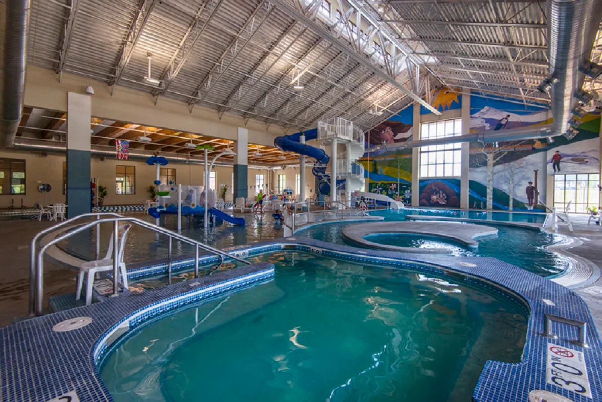 This vibrant interior image captures the Grand Park Rec Center's aquatic area, featuring water slides, swimming pools, colorful murals, and children having fun. The joyful and lively atmosphere highlights the types of family-friendly activities available nearby.