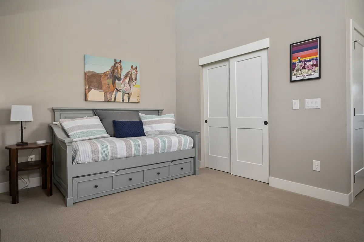 A loft area with a twin daybed, distinctive horse-themed artwork, and a side table with a lamp. The room feels intimate and inviting, ideal for extra family members or children, and emphasizes flexibility and comfort.