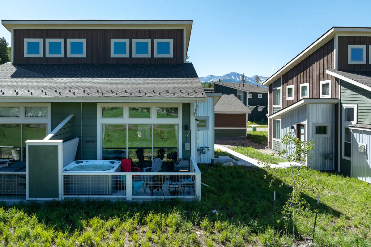 This image features a private patio with a bubbling hot tub and an inviting outdoor seating area, all set against a stunning mountain backdrop. The space looks perfect for relaxing, socializing, or simply soaking in the views at any time of day.